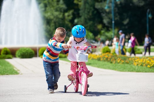 Boy and girl in park learning to ride a bike photo