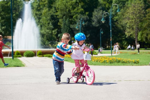 Boy and girl in park learning to ride a bike photo