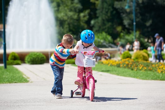 Boy and girl in park learning to ride a bike photo