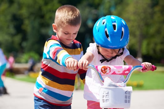 Boy and girl in park learning to ride a bike photo
