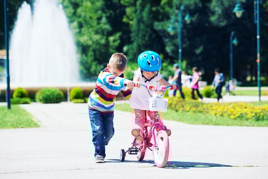 Boy and girl in park learning to ride a bike photo