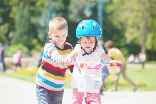Boy and girl in park learning to ride a bike photo