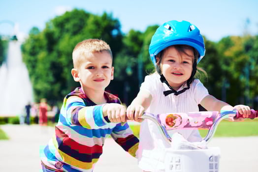 Boy and girl in park learning to ride a bike photo