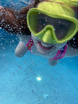 Smiling child in goggles swim, dive in the pool with fun - jump deep down underwater. Healthy lifestyle, people water sport activity on summers. photo