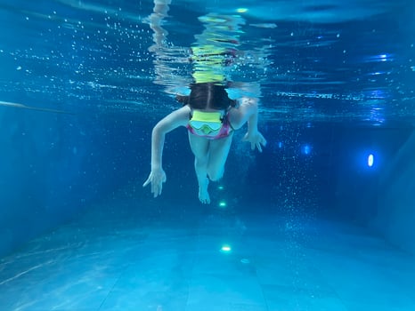 Smiling child in goggles swim, dive in the pool with fun - jump deep down underwater. Healthy lifestyle, people water sport activity on summers. photo