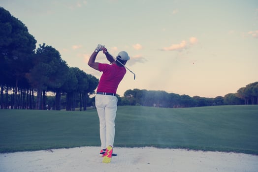 golfer hitting a sand bunker shot on sunset photo