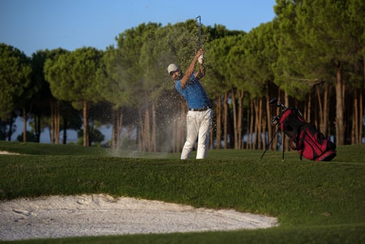 golfer hitting a sand bunker shot on sunset photo