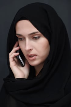 Young muslim businesswoman in traditional clothes or abaya talking on the smartphone photo