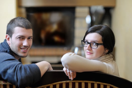 Young romantic couple sitting and relaxing in front of fireplace at home photo