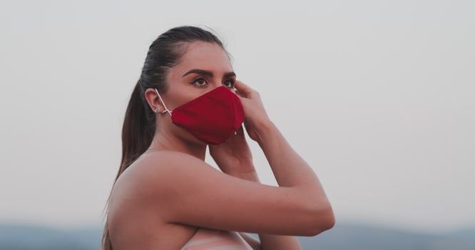 Determined fitness woman in short clothes wearing red protective face mask running outdoors in the city during coronavirus outbreak. Covid 19 and physical jogging activity sport and fitness. photo
