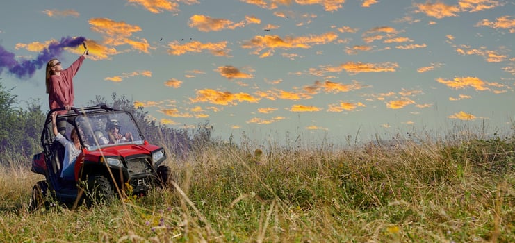 excited people having fun enjoying beautiful sunny day holding colorful torches while driving a off road buggy car photo