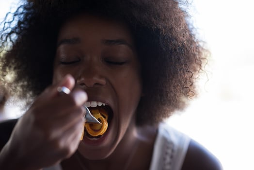 a young African American woman eating pasta photo