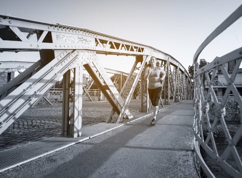 woman jogging across the bridge at sunny morning photo