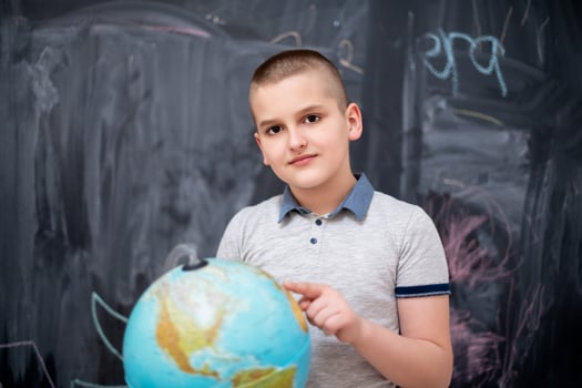 boy using globe of earth in front of chalkboard photo