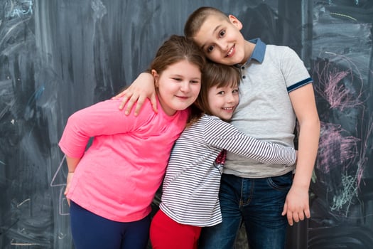group of kids hugging in front of chalkboard photo