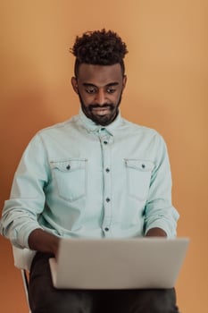 African student using laptop computer to study and make business connections yellow background photo