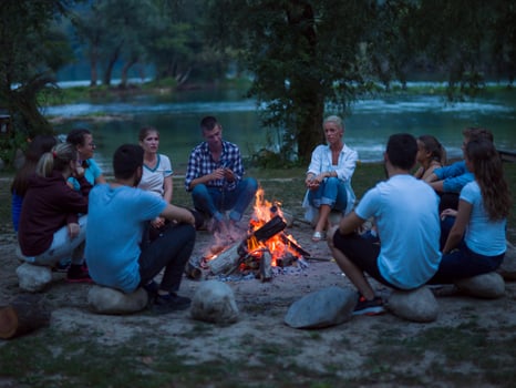 young friends relaxing around campfire photo