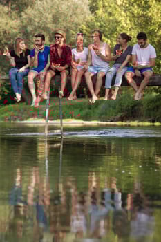 friends enjoying watermelon while sitting on the wooden bridge photo