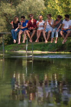 friends enjoying watermelon while sitting on the wooden bridge photo
