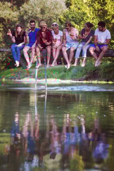 friends enjoying watermelon while sitting on the wooden bridge photo