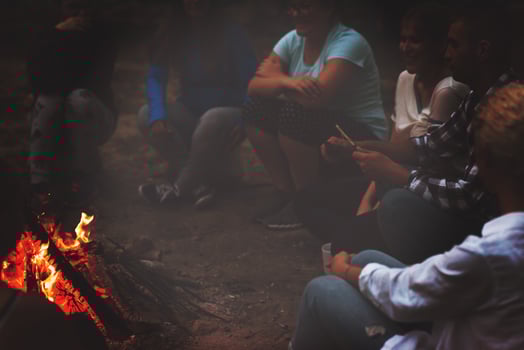 young friends relaxing around campfire photo