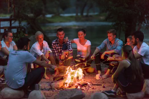 young friends relaxing around campfire photo