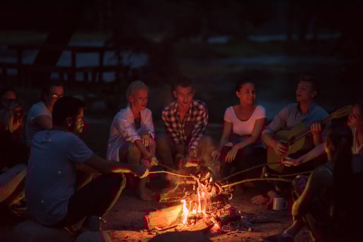 young friends relaxing around campfire photo