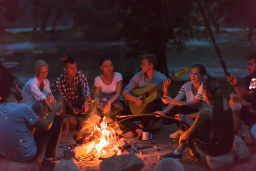young friends relaxing around campfire photo