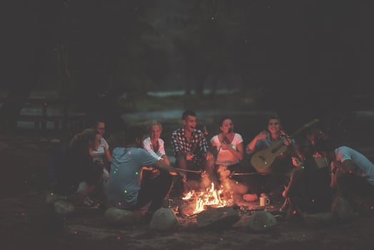 young friends relaxing around campfire photo