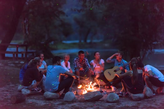 young friends relaxing around campfire photo