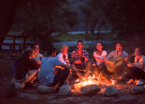 young friends relaxing around campfire photo
