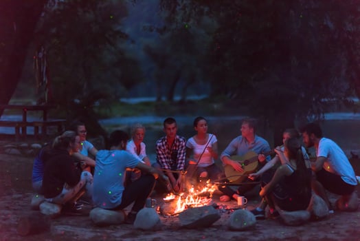 young friends relaxing around campfire photo