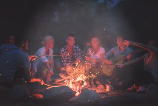 young friends relaxing around campfire photo