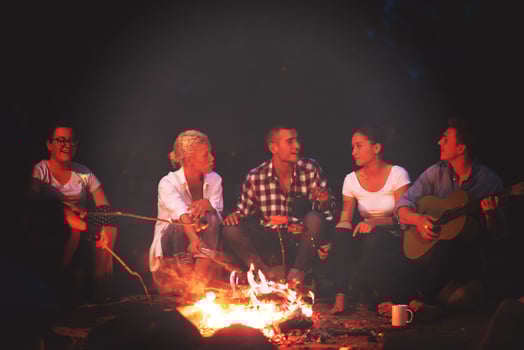 young friends relaxing around campfire photo