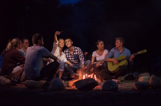 young friends relaxing around campfire photo
