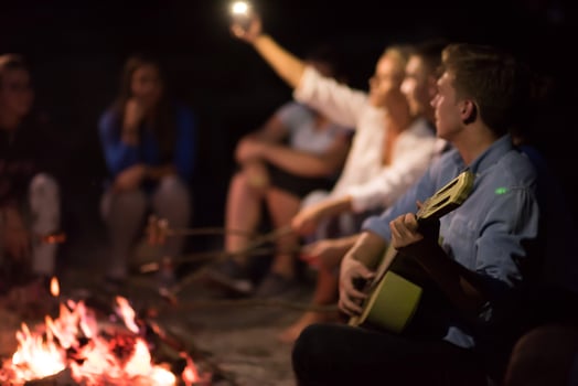 young friends relaxing around campfire photo