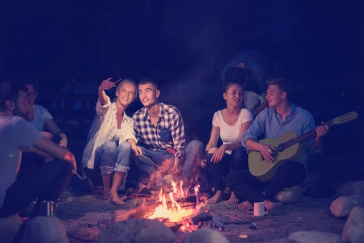 young friends relaxing around campfire photo