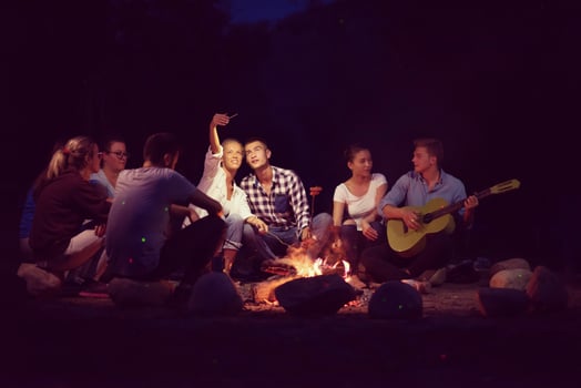 young friends relaxing around campfire photo