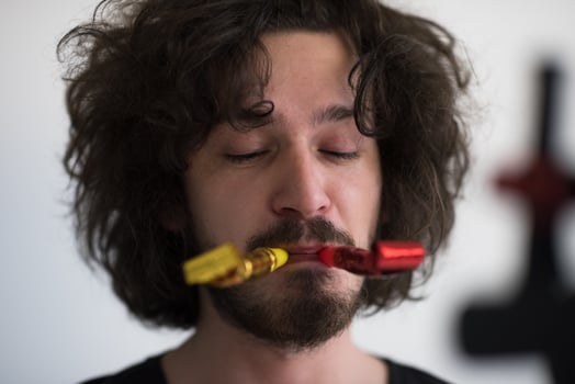 Portrait of a man in party hat blowing in whistle photo