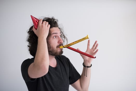 Portrait of a man in party hat blowing in whistle photo