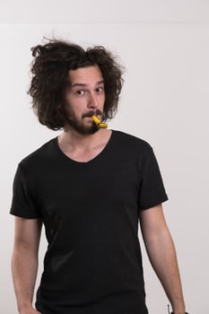 Portrait of a man in party hat blowing in whistle photo