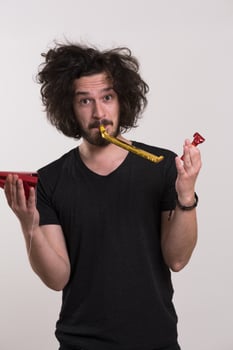 Portrait of a man in party hat blowing in whistle photo