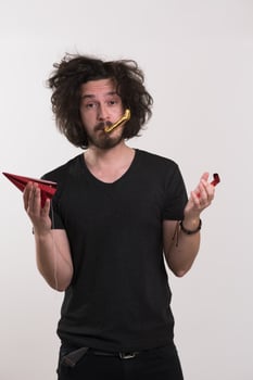 Portrait of a man in party hat blowing in whistle photo