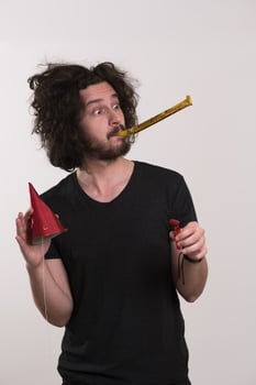 Portrait of a man in party hat blowing in whistle photo