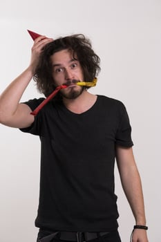 Portrait of a man in party hat blowing in whistle photo
