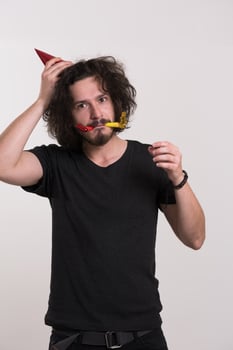 Portrait of a man in party hat blowing in whistle photo