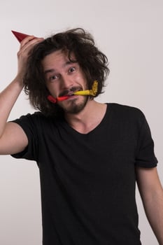Portrait of a man in party hat blowing in whistle photo