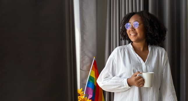 African American girl holding LGBTQ rainbow flag in her bed room for coming out of the closet and pride month celebration to promote sexual diversity and equality in homosexual orientation concept photo