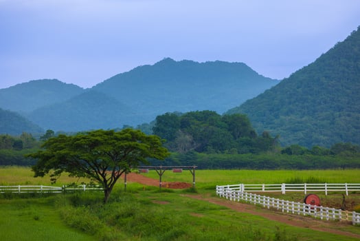 The green ranch behind the mountain has a bright blue sky. photo