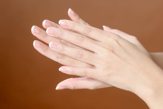 Close up young woman hand is applying cream over brown background , beauty skin care concept photo